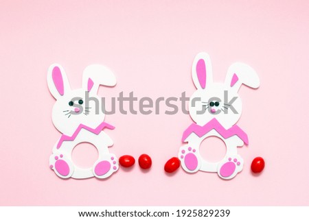 Cute Easter bunnies, red, round, chocolate candies on a pink background. DIY Easter.