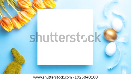 Easter border. Golden, white colour egg in basket with spring tulips, feathers on pastel blue background in Happy Easter decoration. Flat lay, top view