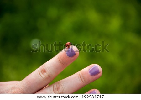Ladybug on finger, with painted nails.