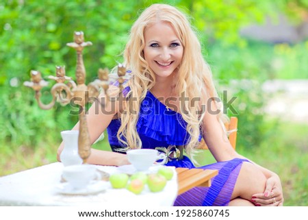 Beautiful young girl with long white hair at the dining table in the garden