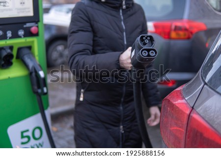 Girl to charge electric car. Hold in hand a cable to charge an electric car. high quality