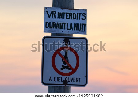 top white sign written in French RV prohibited during the night and the white sign with a red circle written in French open fire prohibited
