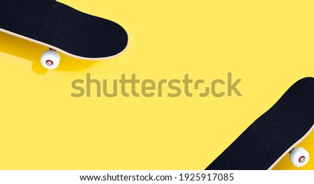 Black skateboard on yellow background. Copy space