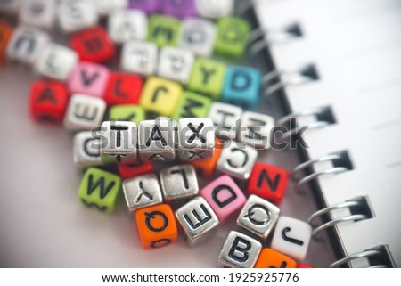 Tiny dice alphabets arranged to display the word 'Tax'. Selective focus on dices with blurred background. 