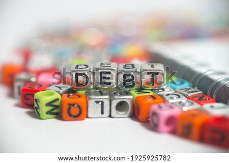 Tiny dice alphabets arranged to display the word 'Debt'. Selective focus on dices with blurred background. 
