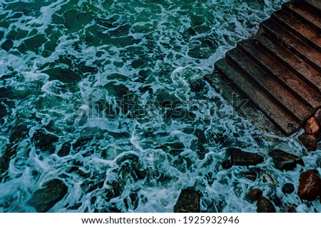Concrete stairways goes down into the sea . Stairs that go down to the water.