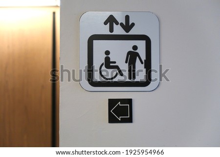 Black and white sign for an elevator and many arrows                              