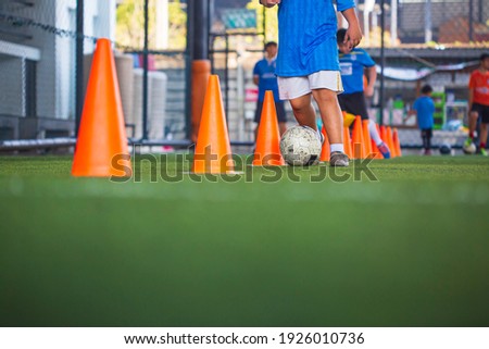 Children playing control soccer ball tactics cone on grass field with for training background Training children in Soccer
