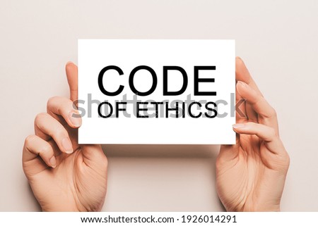 Female hands hold card paper with text Code of Ethics on a yellow background. Business and finance concept