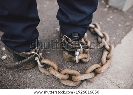 Shallow depth of field (selective focus) details of a policeman who tied a rusty metal chain to his feet during a protest in Bucharest.