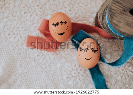 brown easter eggs with painted face lie on a crochet blanket and linen ribbons with wood are decorated to it