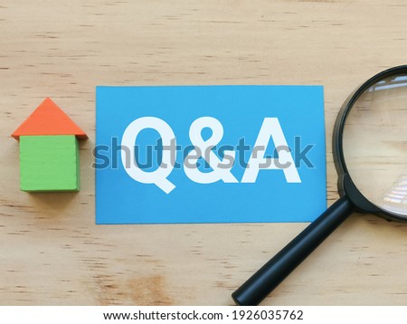 Property concept. Selective focus a piece of blue paper written phrase Q and A with house block and magnifying glass.