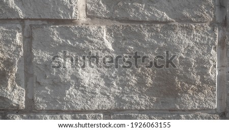 Sandstone stones on the facade of the building. Sedimentary sandstone. It is often mined for use as a building material or as a raw material for manufacturing. Text, background, pattern