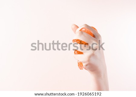 Baby hand squeezes honey to depilation on light beige background
