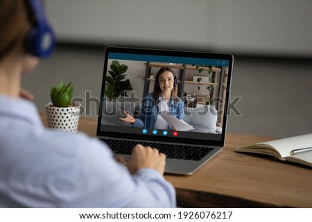 Back view of woman sit at desk at home office have webcam online meeting on computer with colleague. Female talk speak on video call with teacher tutor, engaged in web lesson. Virtual event concept. Royalty-Free Stock Photo #1926076217