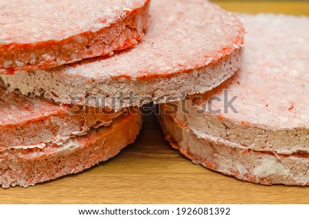 frozen beef hamburger patties, defrost before grilling, stacked on the counter