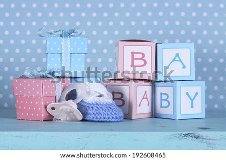 Baby nursery bootie, dummy pacifier and baby letters pink and blue gift boxes against a vintage aqua blue table and polka dot background for baby shower or newborn girl greeting card.