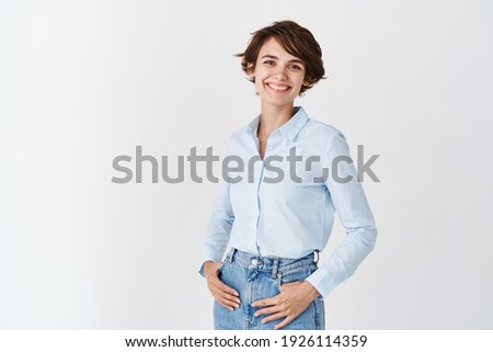 Young working woman in office clothing, smiling and looking at camera, standing on white background. Professional women concept. Royalty-Free Stock Photo #1926114359