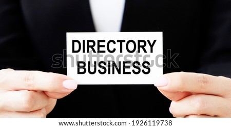 A female businessman holds a business card with a DIRECTORY BUSINESS tectonics.