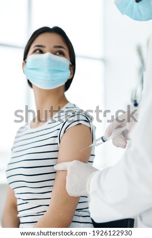 female patient in medical mask making vaccine in hospital