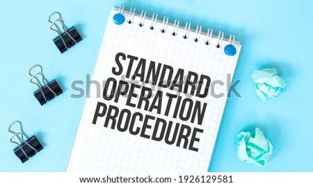 White notepad with text Standard Operation Procedure and office tools on the blue background