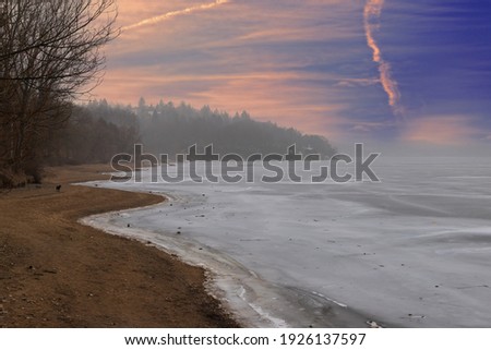 Frozen dam in the city of Brno in the Czech Republic. There is ice on the water. Sky at sunset.