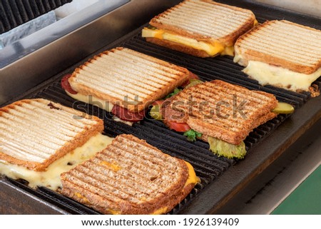 Various kinds of toasts getting ready by toaster man on grill.