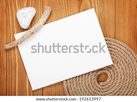 Blank paper card with ship rope over wooden background