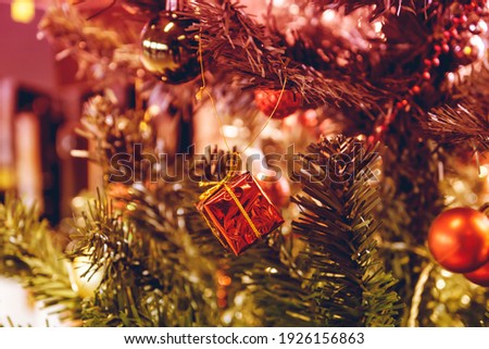 Closeup of Festively Decorated Outdoor Christmas tree with bright red balls and gifts on blurred sparkling fairy background. Defocused garland lights, Bokeh effect.