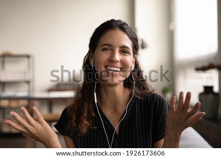 Head shot portrait smiling young woman wearing earphones speaking at camera, teacher leading webinar, enjoying pleasant conversation, making video call, blogger recording vlog for social network Royalty-Free Stock Photo #1926173606