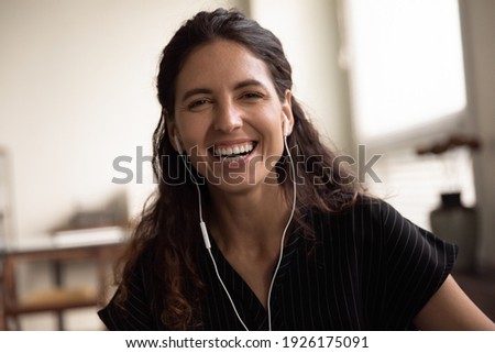 Head shot portrait overjoyed woman wearing earphones laughing at camera, excited happy young female making video call, enjoying pleasant conversation, blogger recording vlog, having fun with webcam