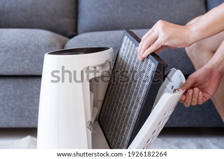 Unrecognizable Asian young man changing - fixing a dirty air purifier HEPA filter after using for a long time. A repairman replacing and installing the air purifier filter. Healthcare and wellbeing. Royalty-Free Stock Photo #1926182264