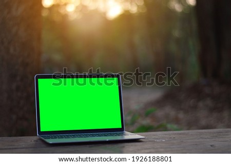 A laptop with a green screen on the table