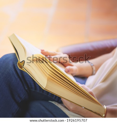 White woman reading a book in an armchair relaxing in nice daylight outside. Copy space. Reading, teaching concept. Background.