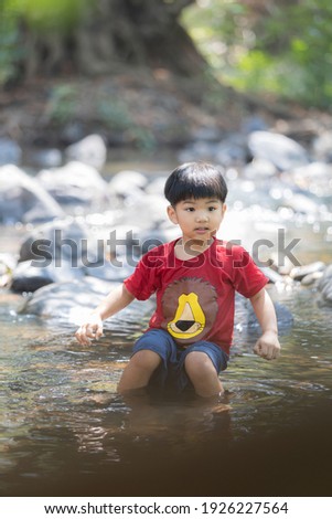 A little boy play water and water-fall , he is enjoy and happy ,swim and play 