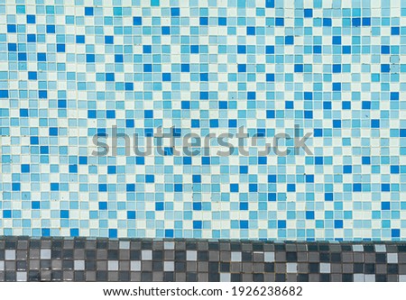 Blue mosaic tiles in swimming pool full of water.