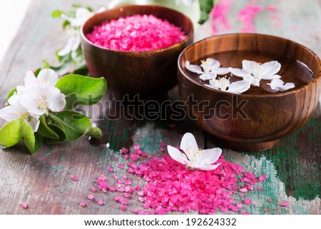 Spa setting on old wooden background. Water with aroma oil, sea salt, flowers. Selective focus, horizontal.