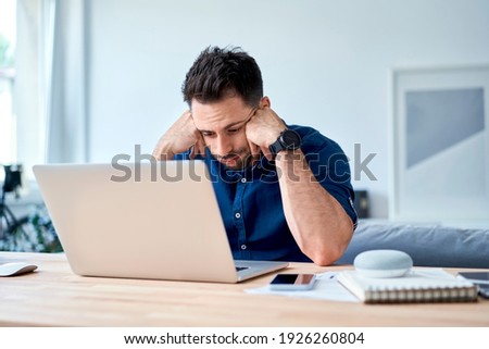 discouraged young man looking with disappointment on laptop while working at home Royalty-Free Stock Photo #1926260804