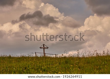 Wooden old cross in the field on a dramatic stormy sky