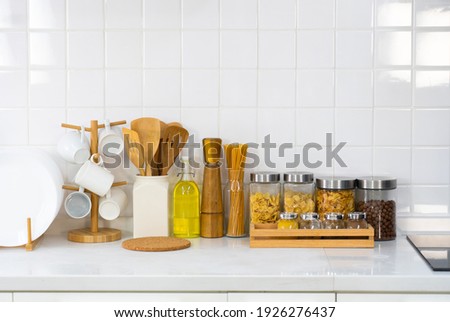 picture of kitchenware, cooking tools, utensils, dish, mug, raw pasta, olive oil, garnish and pepper in white kitchen with copy space
