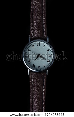 Watch with leather strap on black background