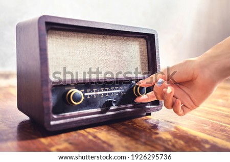 Retro radio tuning. Woman using old vintage music equipment. Adjusting volume or frequency tuner knob. Turning on or off stereo receiver or speaker. Changing channel or station with dial button. Royalty-Free Stock Photo #1926295736