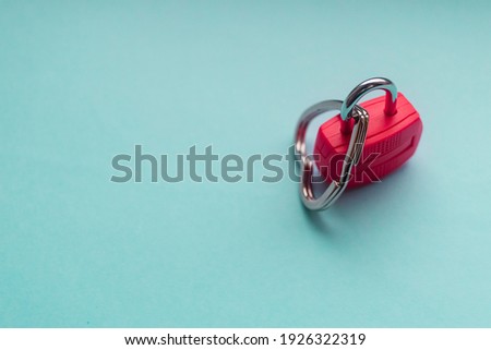 Single padlock lock with attached locked in heart charm in the baby blue turquoise flat lay background 