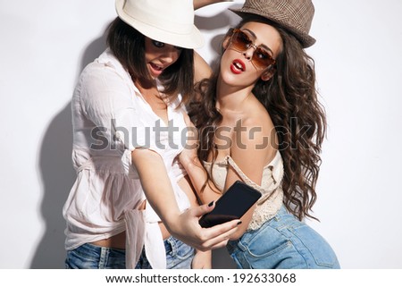 two young women taking picture of them selfs with mobile