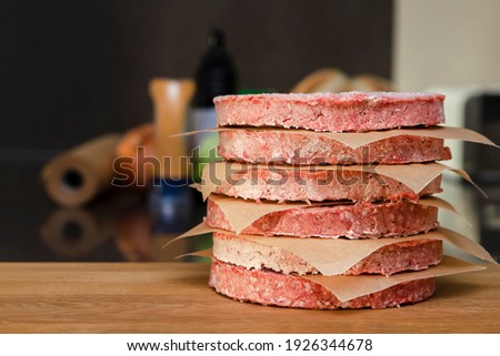 Frozen beef burger patties are placed on a wooden cutting board before cooking. Freezing in the freezer