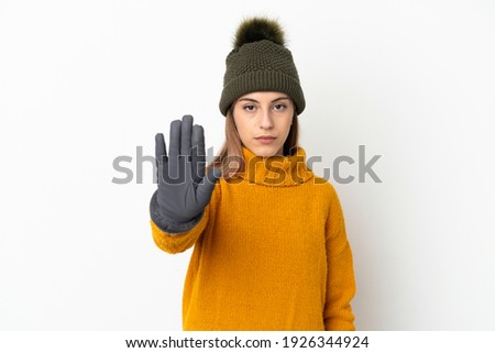Young girl with winter hat isolated on white background making stop gesture