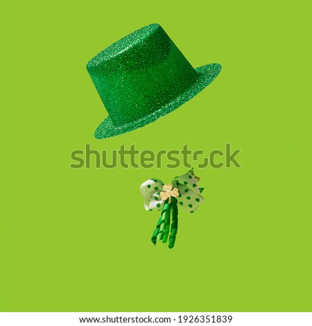 St. Patrick's Day concept. Irish glittery hat, and bow with shamrock leaf clovers in gold and green colors, and curly ribbon In on green background.