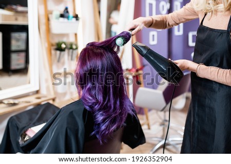 Beautiful hairstyle of young adult woman with purple hair in hair salon. Royalty-Free Stock Photo #1926352904