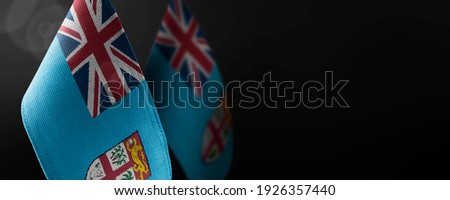 Small national flags of the Fiji on a dark background