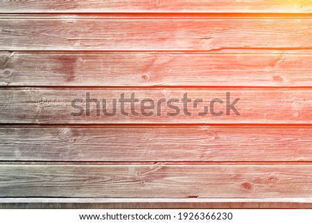 The sun rays fall on the old fence. Rustic background. Wooden wall of an old house. Horizontal gray boards close up. Place for text, copy space.